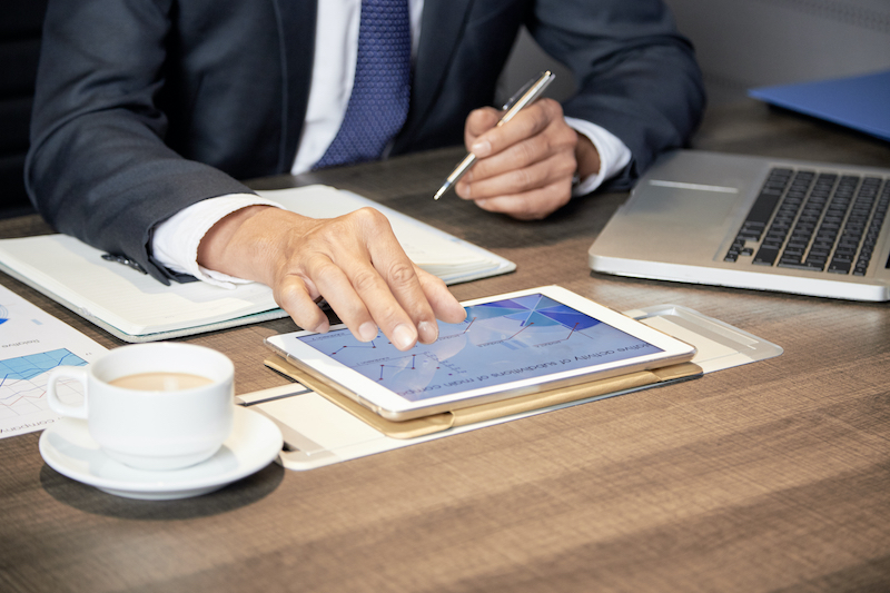 Crop businessman using tablet at table