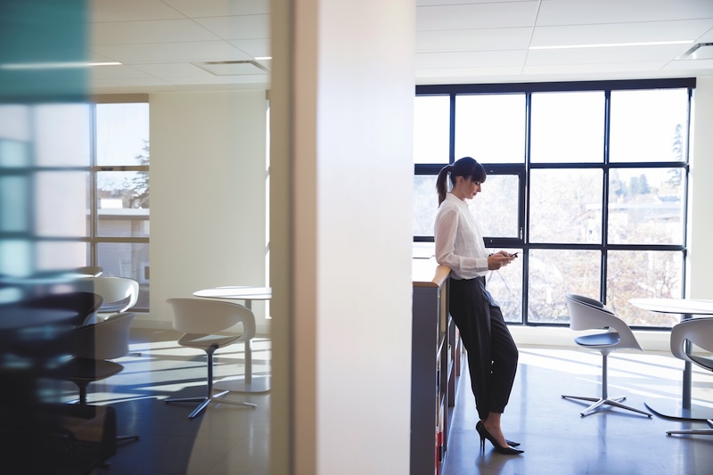 Businesswoman texting with cell phone in office